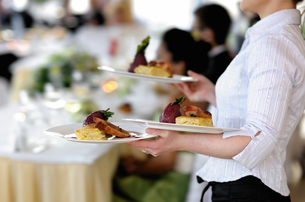 A vibrant office party with an assortment of gourmet finger foods, desserts, and beverages displayed on a decorated table.