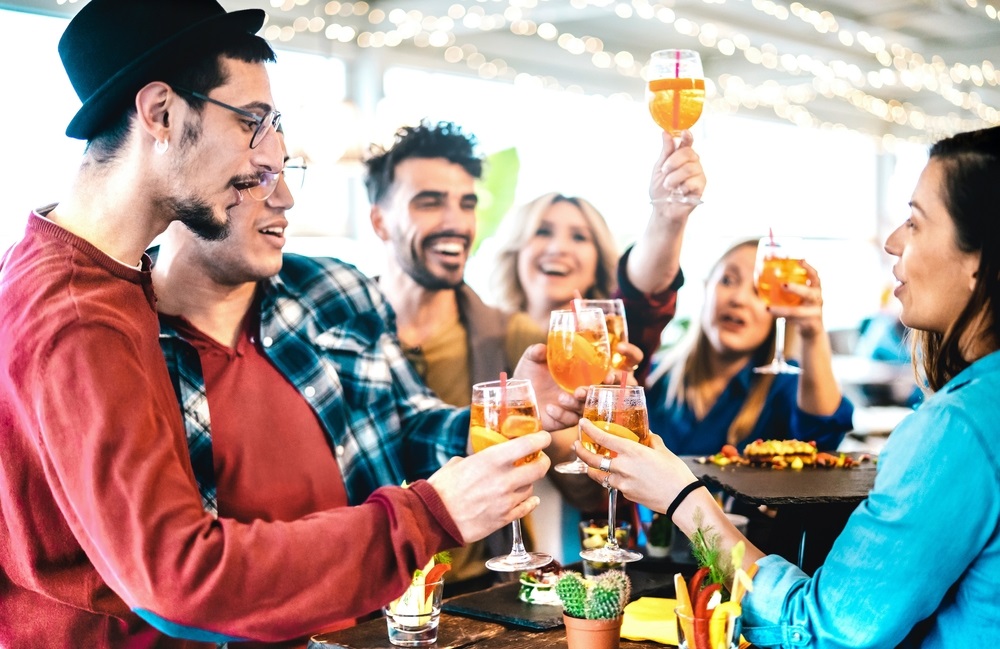 A vibrant office party with an assortment of gourmet finger foods, desserts, and beverages displayed on a decorated table.